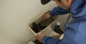 Plumber working in back of toilet